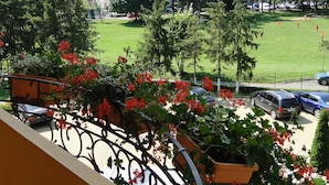 Ein Balkon mit Blick auf einen grünen Park, einen Parkplatz und ein Gebäude im Hintergrund.
