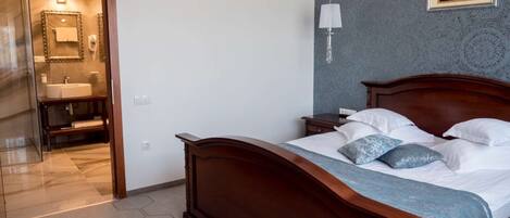 Un dormitorio con cama de madera, una mesita de noche, una lámpara de noche y un cuadro colgado en la pared.