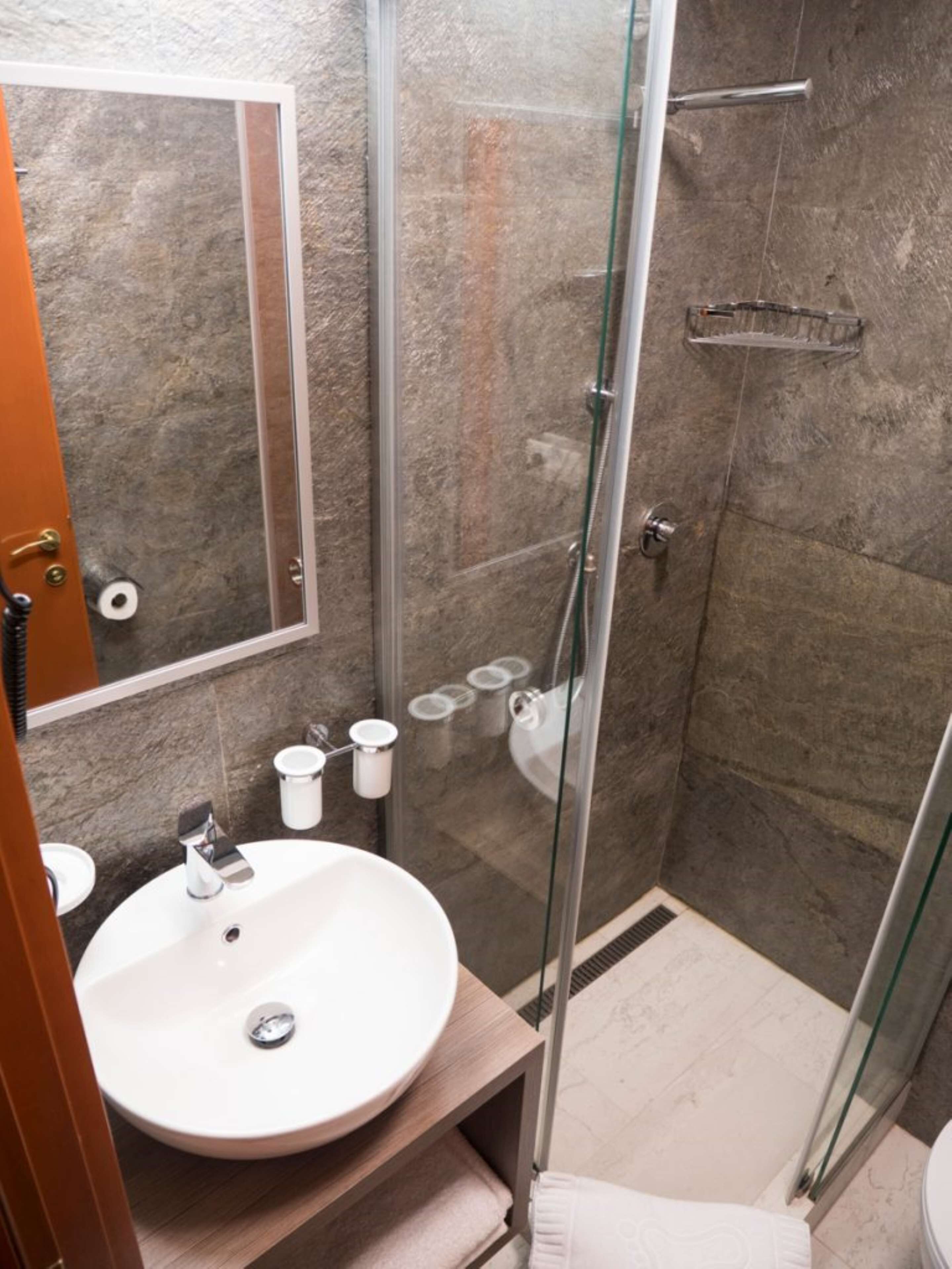 A modern bathroom with a glass-enclosed shower, a white sink, and a mirror.
