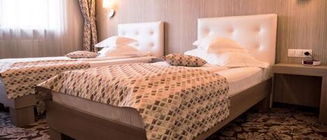 Habitación de hotel con dos camas, una mesita de noche, un reloj y una lámpara fijada a la pared.