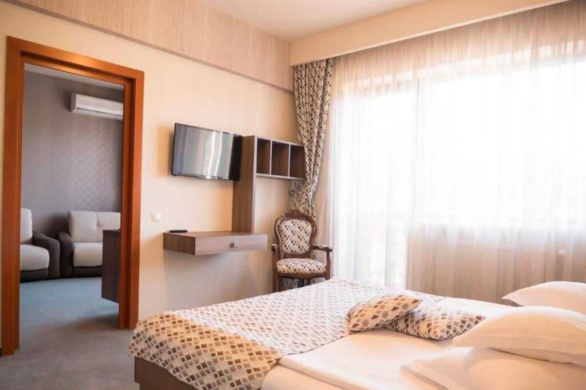 Quarto de hotel com cama, televisão, cadeira e secretária.