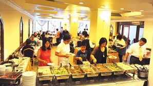 A buffet with multiple food stations and people serving themselves. - Panorama Hotel (Yangon)