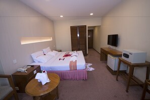 A hotel room with a bed, bedside table, TV, and a small kitchenette. - Panorama Hotel (Yangon)