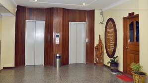 A lobby with wooden paneling, a reception desk, a statue, and a level plan sign. - Panorama Hotel (Yangon)
