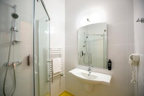 Un baño moderno con cabina de ducha de vidrio, un lavamanos blanco y un espejo encima.