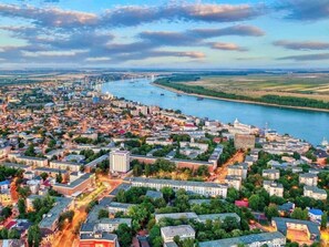 An aerial view of a city with a river, buildings, and greenery. - Dunarea Hotel (Galati)