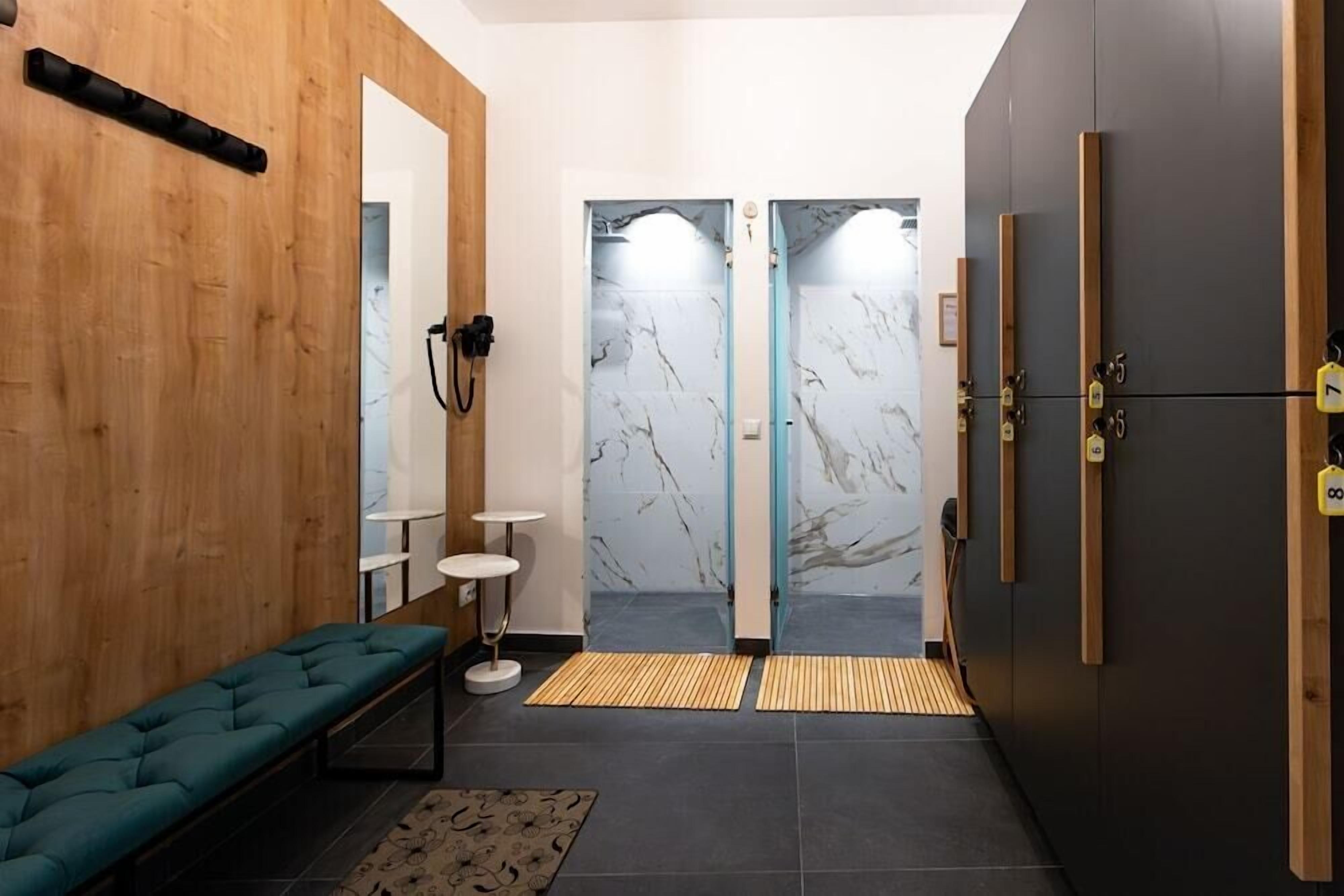 A modern bathroom with a bench, a mirror, a towel rack, and a shower area with marble walls.