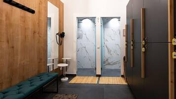 A modern bathroom with a bench, a mirror, a towel rack, and a shower area with marble walls.