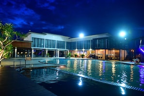 A swimming pool with a modern building in the background. - Prajaktra Design Hotel (Udon Thani)