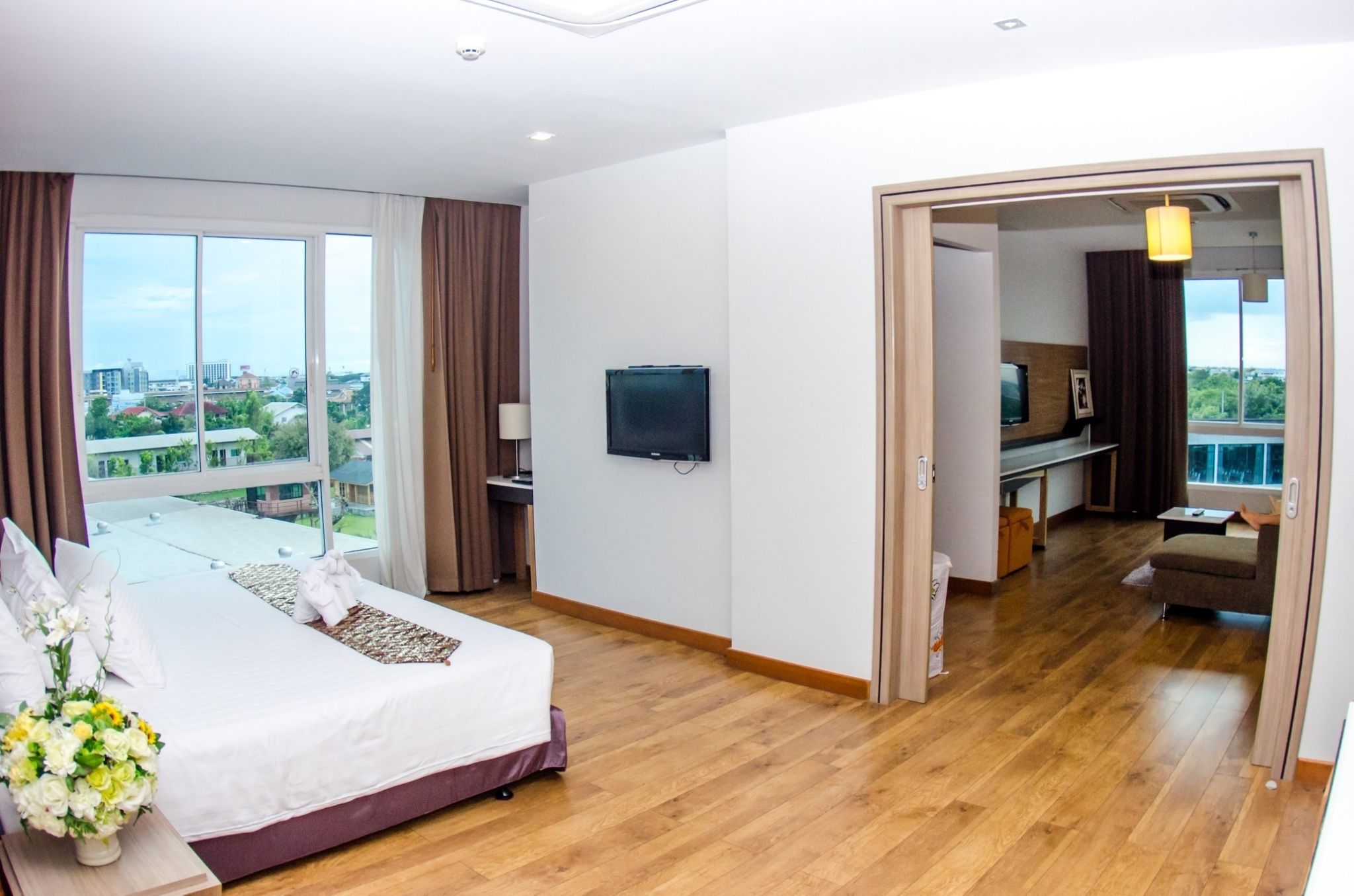 A hotel room with a large bed, a TV, a desk, and a view of the city.