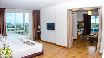 A hotel room with a large bed, a TV, a desk, and a view of the city.