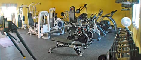 A gym with various exercise equipment, including treadmills, weight machines, and free weights.
