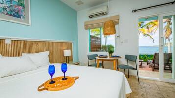 Une chambre d’hôtel avec un lit, un coin repas comprenant des chaises et une table, et une vue sur l’océan.