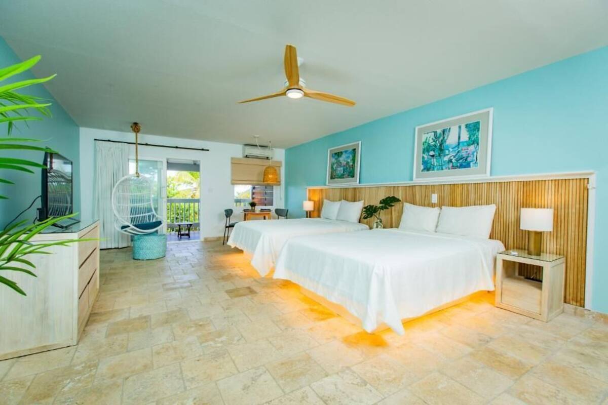 Habitación de hotel con dos camas, ventilador de techo, televisión y vista al exterior.