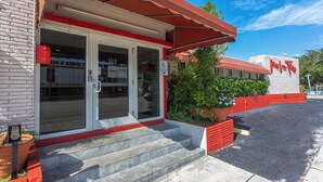 A building with a red awning, a wheelchair-accessible entrance, and a sign indicating low rates. - Beach and Town Motel (Hollywood)