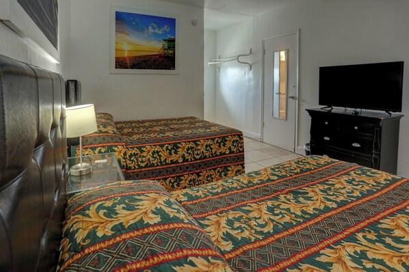 Habitación de hotel con dos camas, televisión, cómoda y un cuadro en la pared.