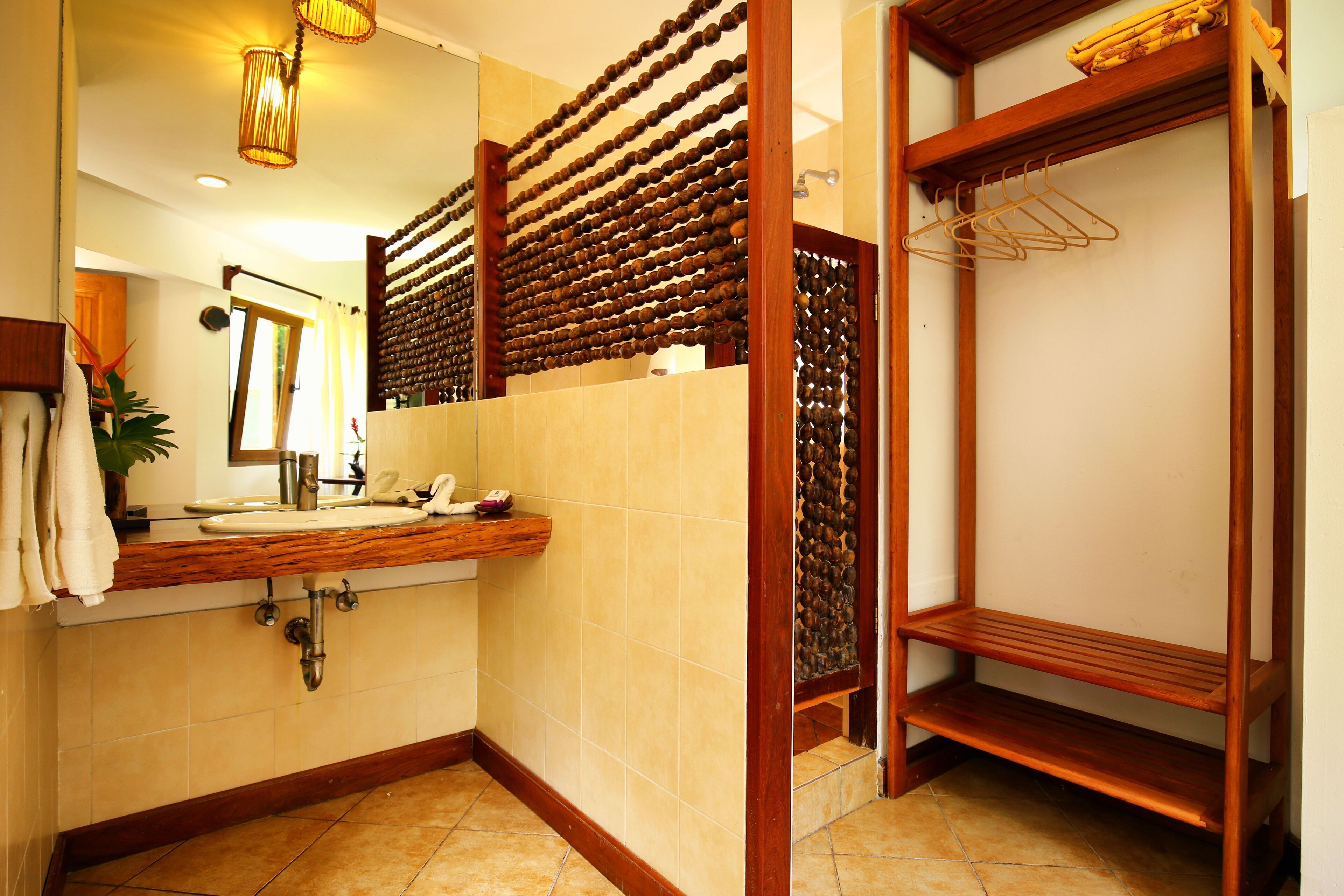 A bathroom with a wooden vanity, a mirror, a sink, and a shower area.