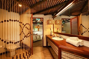 A bathroom with a wooden vanity, a large mirror, and a hanging light fixture.