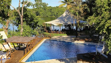 Alberca al aire libre, sombrillas en la alberca y camastros