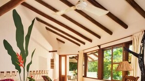 A room with two beds, a rocking chair, a large window, and a ceiling fan. - Hotel Villa Maya (Flores)