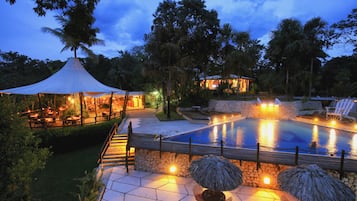 Una piscina al aire libre, sombrillas, sillones reclinables de piscina