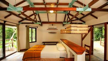 A bedroom with a bed, wooden ceiling beams, an air conditioning unit, and a view through a glass door.