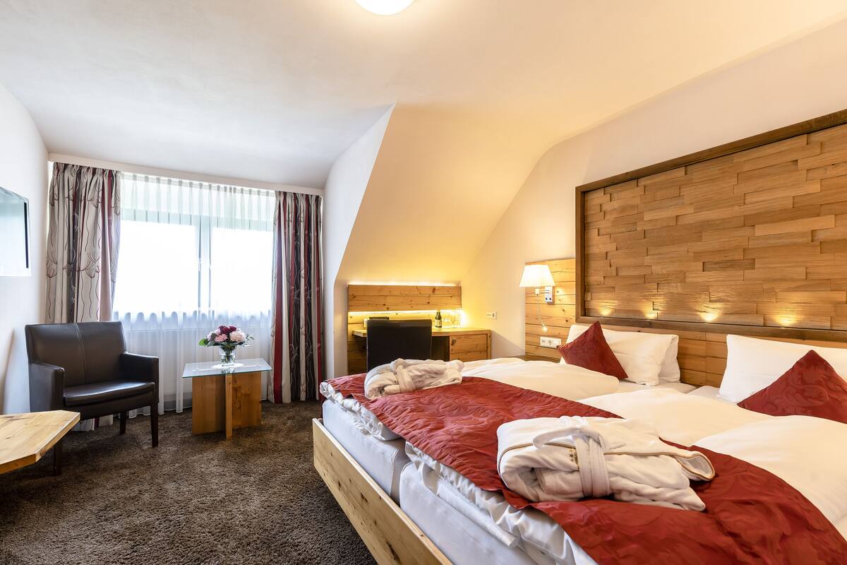 A hotel room with a bed, a desk, a chair, and a small table.