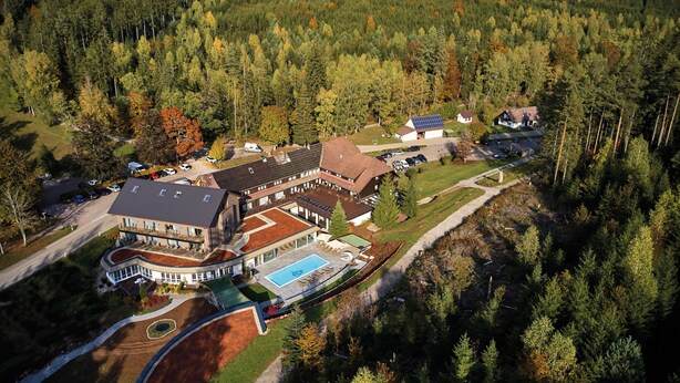 A large building with multiple sections, a swimming pool, and a parking area surrounded by dense forest. - Hotel Restaurant Waldsägmühle (Pfalzgrafenweiler)