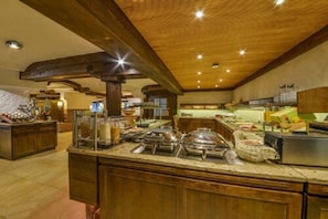 A buffet area with multiple food stations and a wooden ceiling.