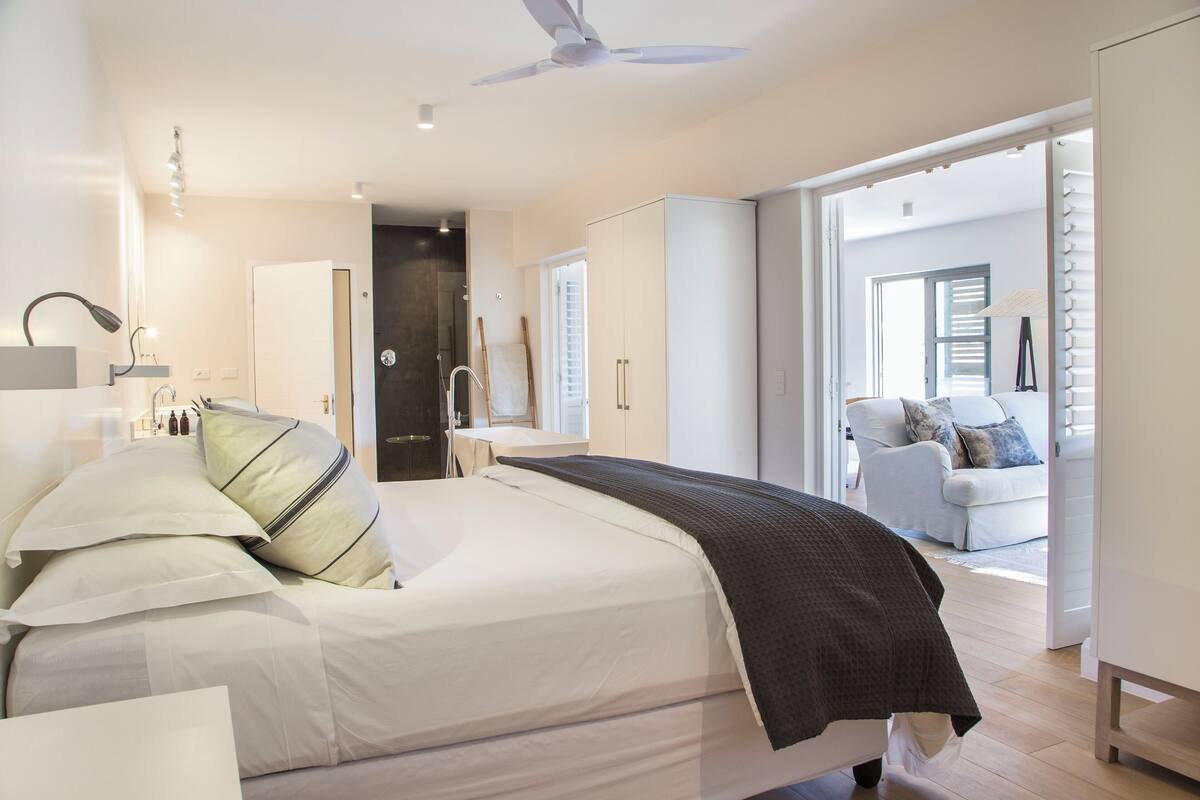 A modern bedroom with a bed, bedside table, and a view of a living area.