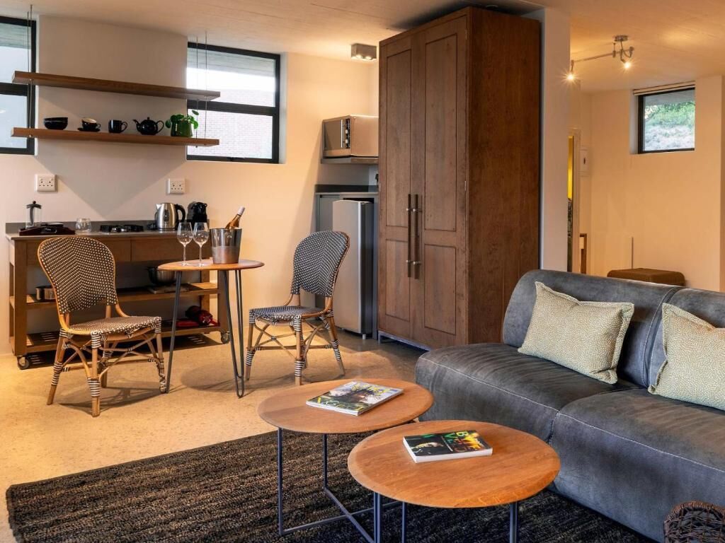 Un espai habitable compacte amb cuineta, un sofà, dues cadires i una taula de menjador.