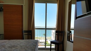 A hotel room with a bed, a chair, a TV, and a balcony with a view of the sea. - Varadero Palace Hotel I (Florianópolis)
