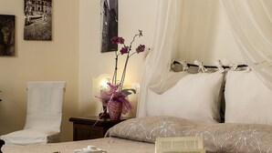 Habitación de hotel con cama, una silla, mesita de noche con lámpara y obras de arte en las paredes.