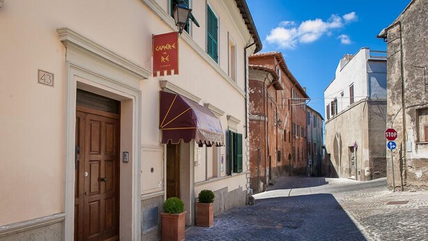 Una estrecha calle adoquinada con edificios históricos, una puerta de madera y un estandarte rojo.