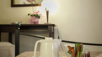 Una camera d'albergo con un letto, un comodino con una lampada, un quadro incorniciato e una piccola TV appesa al muro.