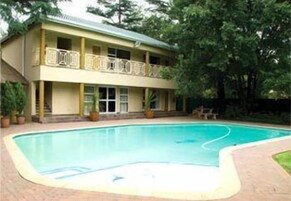 Um edifício de dois andares com piscina na frente.