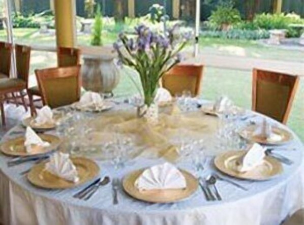 A round table set for a meal with a white tablecloth, gold plates, and silverware.