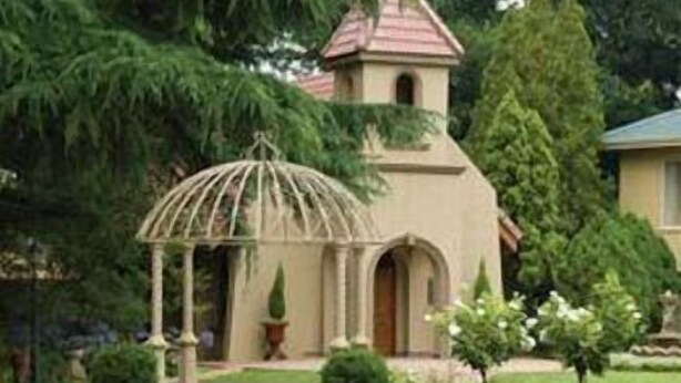 Un edificio con una pequeña torre y un pabellón en el jardín.
