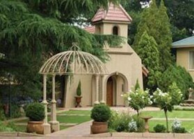 Um edifício com uma torre pequena e um gazebo no jardim.