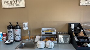 A breakfast bar with coffee makers, a fruit display, and a toaster.