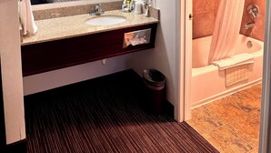 A hotel bathroom with a sink, mirror, towel rack, and shower.