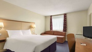 Een hotelkamer met een bed, een bureau, een stoel en een televisie.