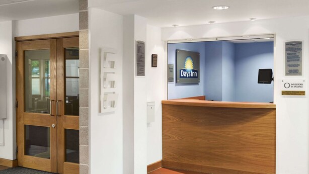 Een receptiegedeelte met een Days Inn bord, een receptiebalie en een wandplaket.