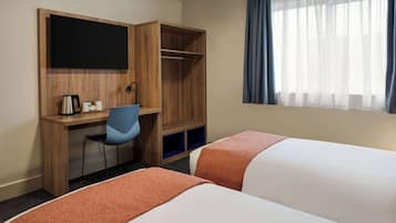 A hotel room with two beds, a desk with a chair, a television, and a window with curtains.