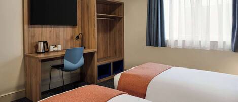 A hotel room with two beds, a desk with a chair, a television, and a window with curtains.