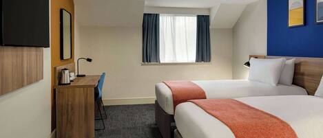 Een hotelkamer met twee bedden, een bureau, een stoel, een televisie, een raam met gordijnen en een plafondlamp.