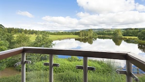A scenic view from a balcony overlooking a lake with surrounding greenery and hills. - Days Inn by Wyndham Lockerbie Annandale Water (Lockerbie)