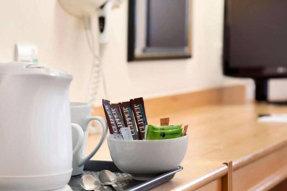 A kitchen area with a white kettle, a mug, and a bowl containing chocolate bars and a green item.