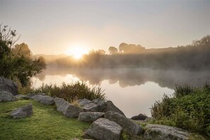 A serene lakeside scene with a clear view of the sunrise, calm water, and surrounding greenery. - Days Inn by Wyndham Lockerbie Annandale Water (Lockerbie)