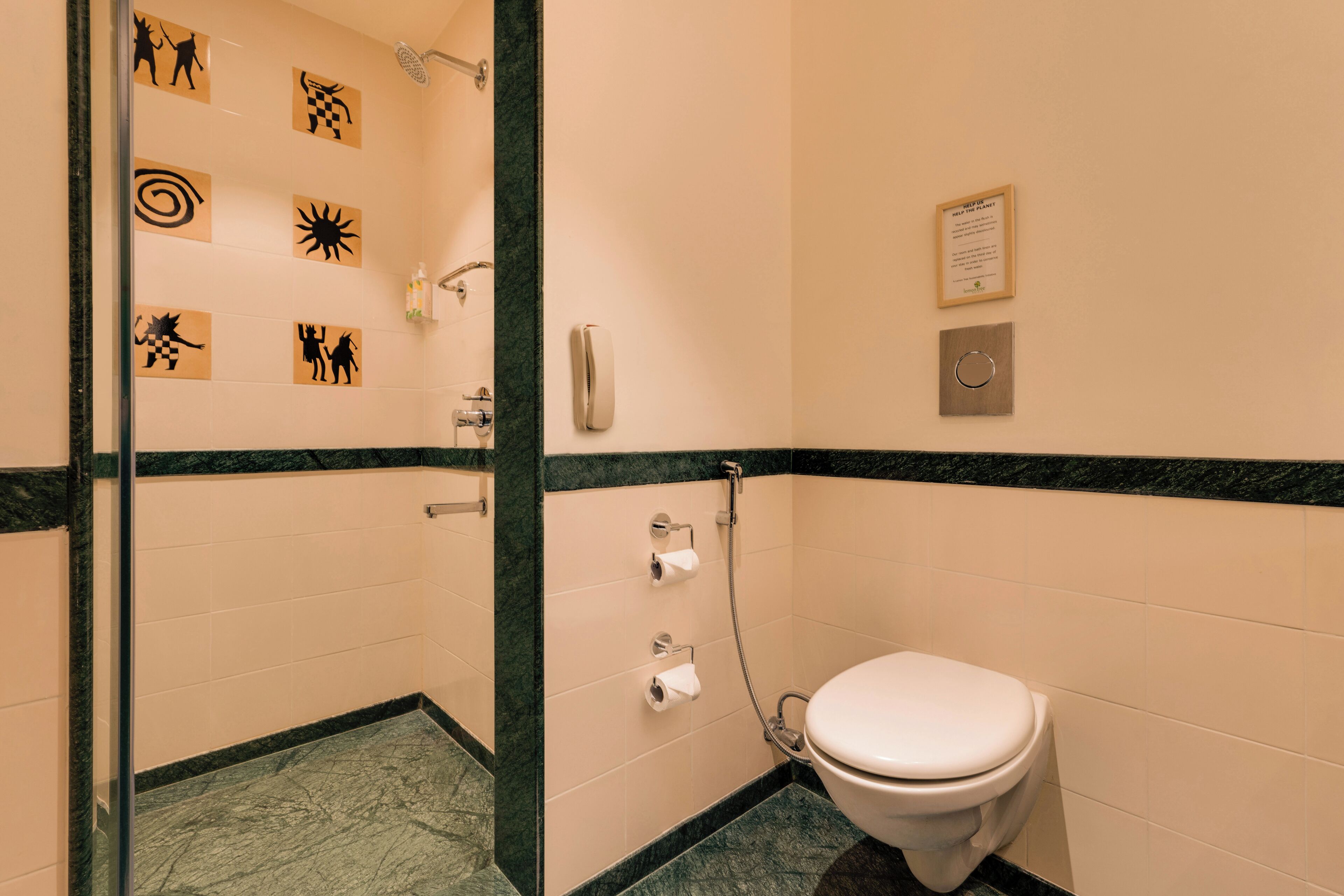 A bathroom with a toilet, a shower, and a hand dryer. There are also toilet paper holders and a hand sanitizer dispenser.